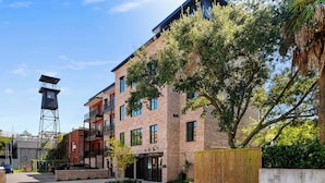 A multi-story brick building with a fire tower, a gated entrance, and a parking area. - Fire Tower | King Street Condo - Walk Everywhere! (Charleston)