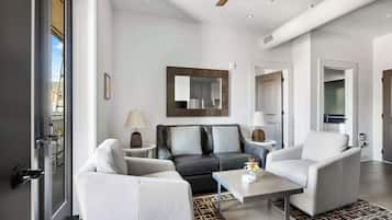 A modern living room with a sofa, armchairs, a coffee table, and a large mirror on the wall.
