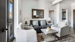 Una sala moderna con un sofá, sillones, una mesita de centro y un espejo grande en la pared.