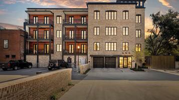 Un immeuble résidentiel à plusieurs étages, doté d’un garage, d’une façade en briques et de balcons.