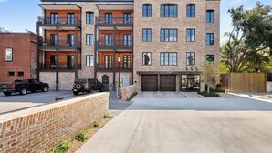 A multi-story residential building with a brick facade, balconies, and a garage. - Fire Tower | Private 1BR King Suite + Rooftop View (Charleston)