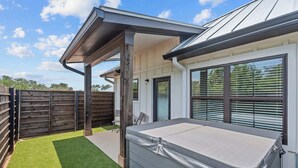 A covered outdoor area with a patio, a wooden fence, and a mattress on the ground. - Eagle's Villa 103 - Hot Tub, 5 Min to Main (Fredericksburg)