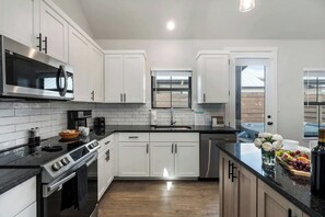 A modern kitchen with white cabinets, stainless steel appliances, and a black countertop.