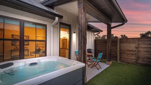 Ein Whirlpool in einem Garten mit einer Holzterrasse, einem Holzzaun und einem Rasen.