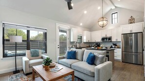 Eine moderne Küche mit weißen Schränken, Edelstahlgeräten und einem Essbereich mit einer Couch und einem Couchtisch.