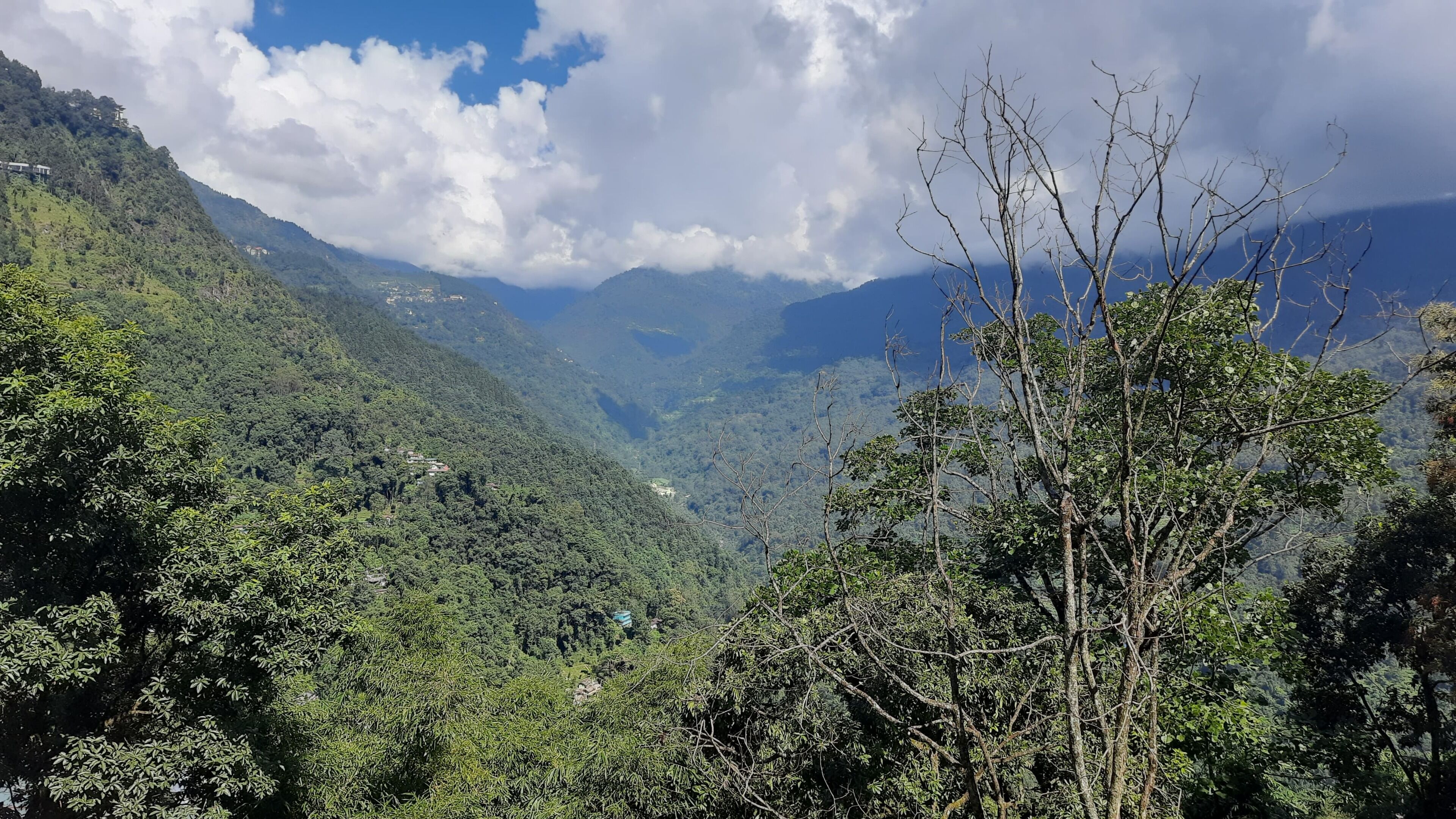 Paisagem montanhosa com vegetação densa e edifícios espalhados.