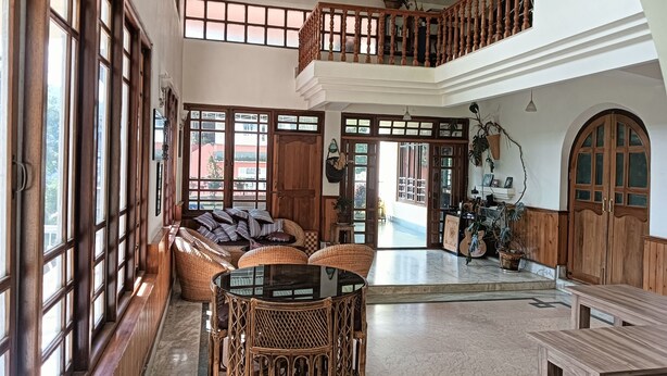 Un vaste espace de vie doté d’un haut plafond, de grandes fenêtres, d’un balcon et d’un coin repas avec des meubles en osier.