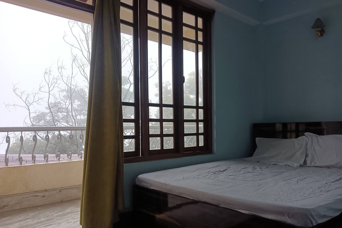 A room with a bed, a window with a curtain, and a balcony with a railing.