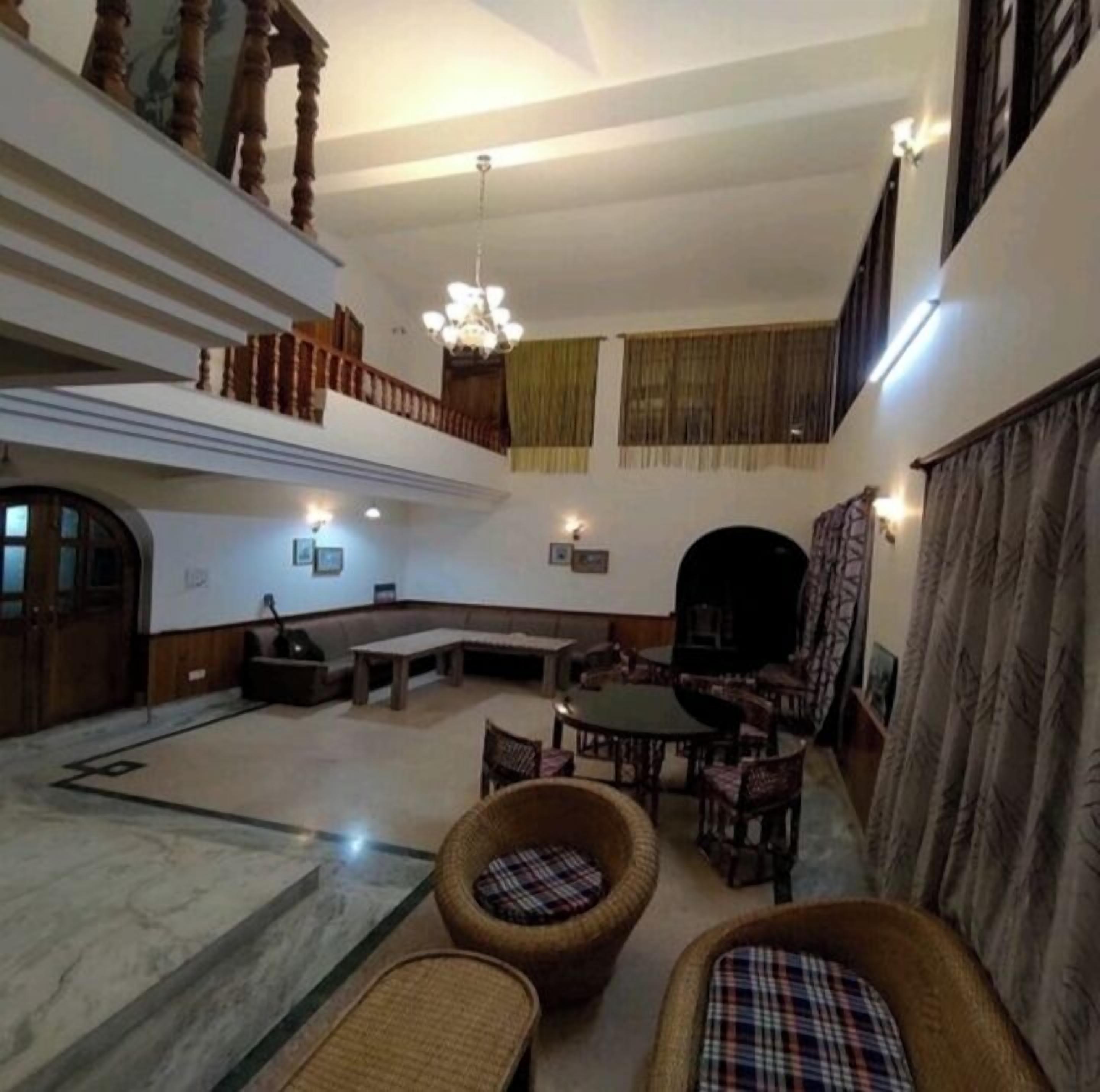 A spacious living area with a high ceiling, a fireplace, and a seating area with wicker chairs and a round table.