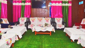 A room with a sofa set, tables, and a TV mounted on the wall. - Snow View Homestay (Sainj)