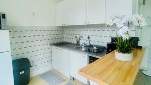 A modern kitchen with white cabinets, a stainless steel sink, and a wooden countertop. - Spacious and bright, a real "coup de coeur" near the metro and RER station (La Courneuve)
