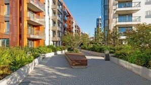 A modern apartment building with balconies, a paved walkway, and landscaped areas. - Brabank 20 by Grand Apartments (Gdansk)