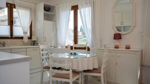A white kitchen with a round table, chairs, and a cabinet. - Anna Maria Family House#1 (Kalampaka)
