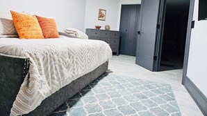 A bedroom with a bed, a dresser, a wardrobe, and a patterned rug. - High-end 2Bdrm Garden Apt. Where Comfort Meets Style (Chicago)