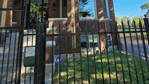 A multi-story building with a brick facade, large windows, and a gated entrance. - High-end 2Bdrm Garden Apt. Where Comfort Meets Style (Chicago)