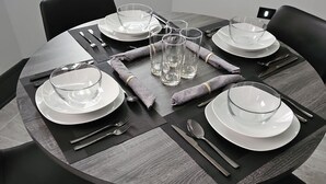 A round dining table with four chairs, set with white plates, clear glasses, and cutlery. - High-end 2Bdrm Garden Apt. Where Comfort Meets Style (Chicago)