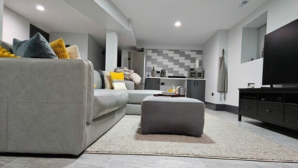 A modern living room with a grey sofa, ottoman, and a flat-screen TV. - High-end 2Bdrm Garden Apt. Where Comfort Meets Style (Chicago)