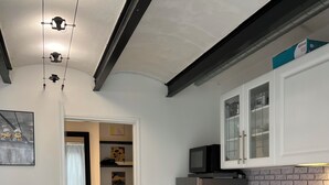 A modern kitchen with white cabinetry, a black countertop, and a brick backsplash.