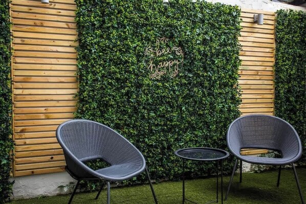 A garden with a wooden wall, a green hedge, and two chairs. - The Cove - Roker Sea Front - Vacant Nests (Roker)