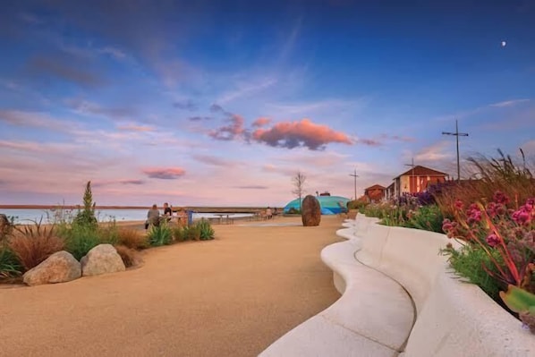 A pathway leading to a building with a view of the water and a sunset sky.