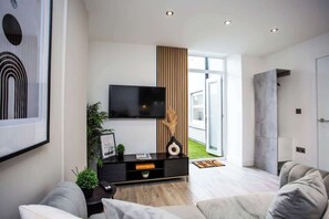 Un salon moderne doté d’un téléviseur à écran plat, d’un mur décoratif en bois et d’une grande fenêtre.