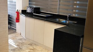 Una cocina moderna con encimera negra, pileta de acero inoxidable y un extintor.