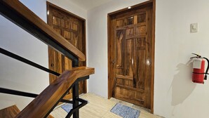 Una escalera de madera que conduce a una habitación con dos puertas de madera y un extintor en la pared.