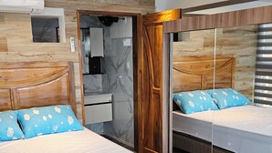 Un dormitorio moderno con dos camas, cabecero de madera, un banco y un armario empotrado.