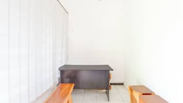 A room with a dark wooden desk, two wooden benches, and a white wall.