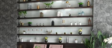 A living room with a sofa, a coffee table, and a wall-mounted shelf unit with various decorative items.