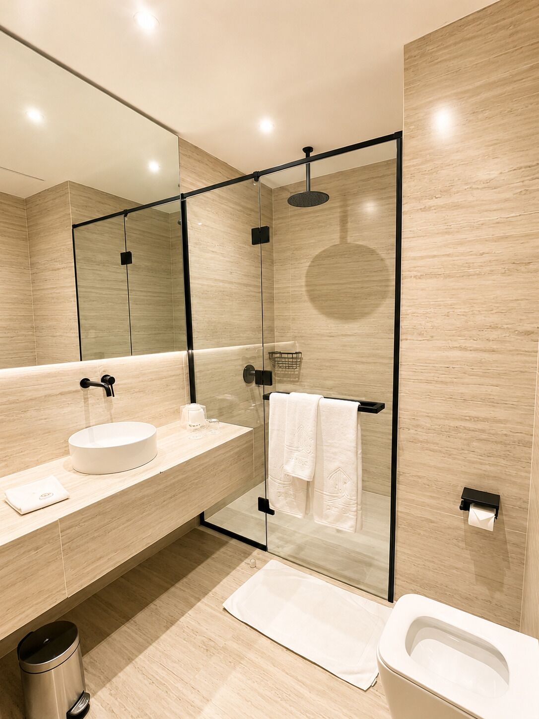 A modern bathroom with a glass-enclosed shower, a round sink, and a toilet.