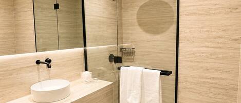 A modern bathroom with a glass-enclosed shower, a round sink, and a toilet.