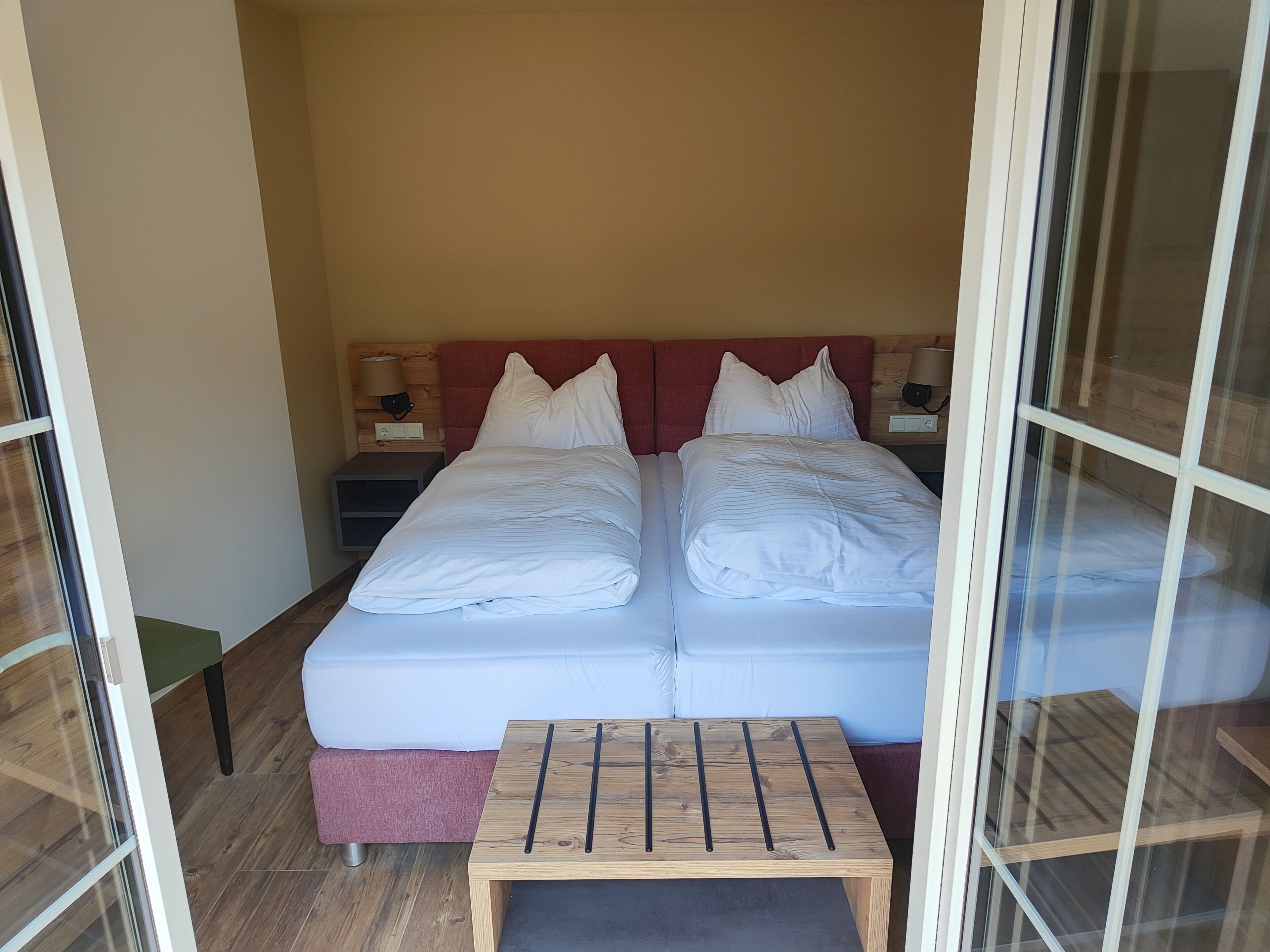 A double bed with white linens, a small wooden table, and two bedside tables with lamps.