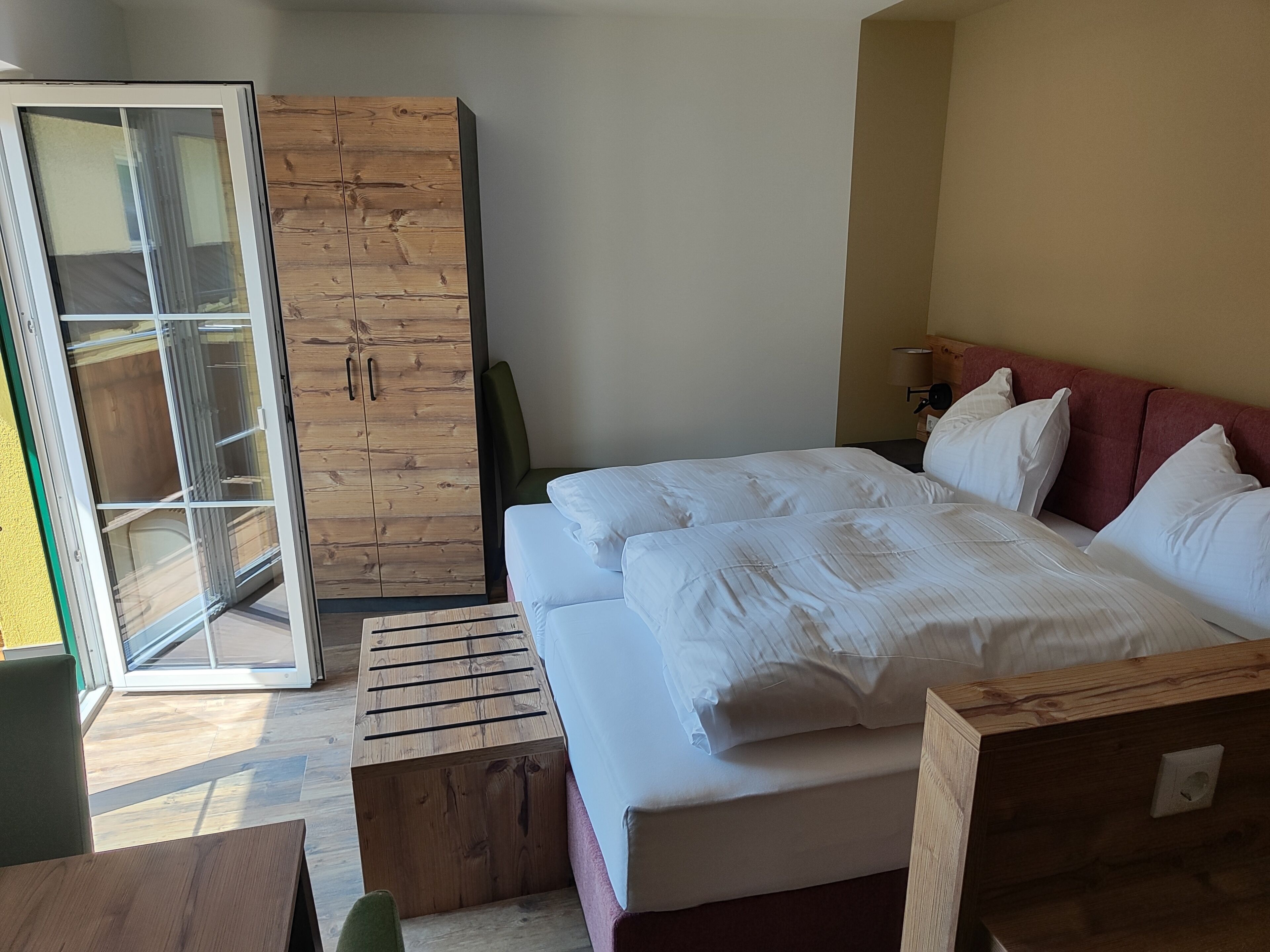 Un dormitorio con cama, armario de madera y puerta corrediza de vidrio que da a un balcón.
