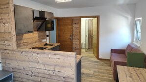 A modern kitchen with wooden accents, a built-in microwave, and a wooden-framed door leading to a bathroom. - Hotel Bad goisern (Bad Goisern)