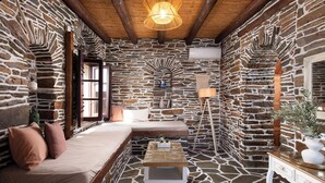 A stone-walled room with a wooden ceiling, a bed, a bedside table, and a lamp. - Andros Serenity Retreat - Adults Only (Andros)