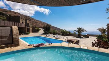 Una piscina al aire libre de temporada, sillones reclinables de piscina