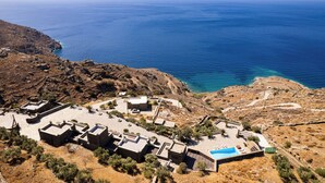 An aerial view of a coastal property with multiple buildings, a swimming pool, and a clear view of the sea. - Andros Serenity Retreat - Adults Only (Andros)