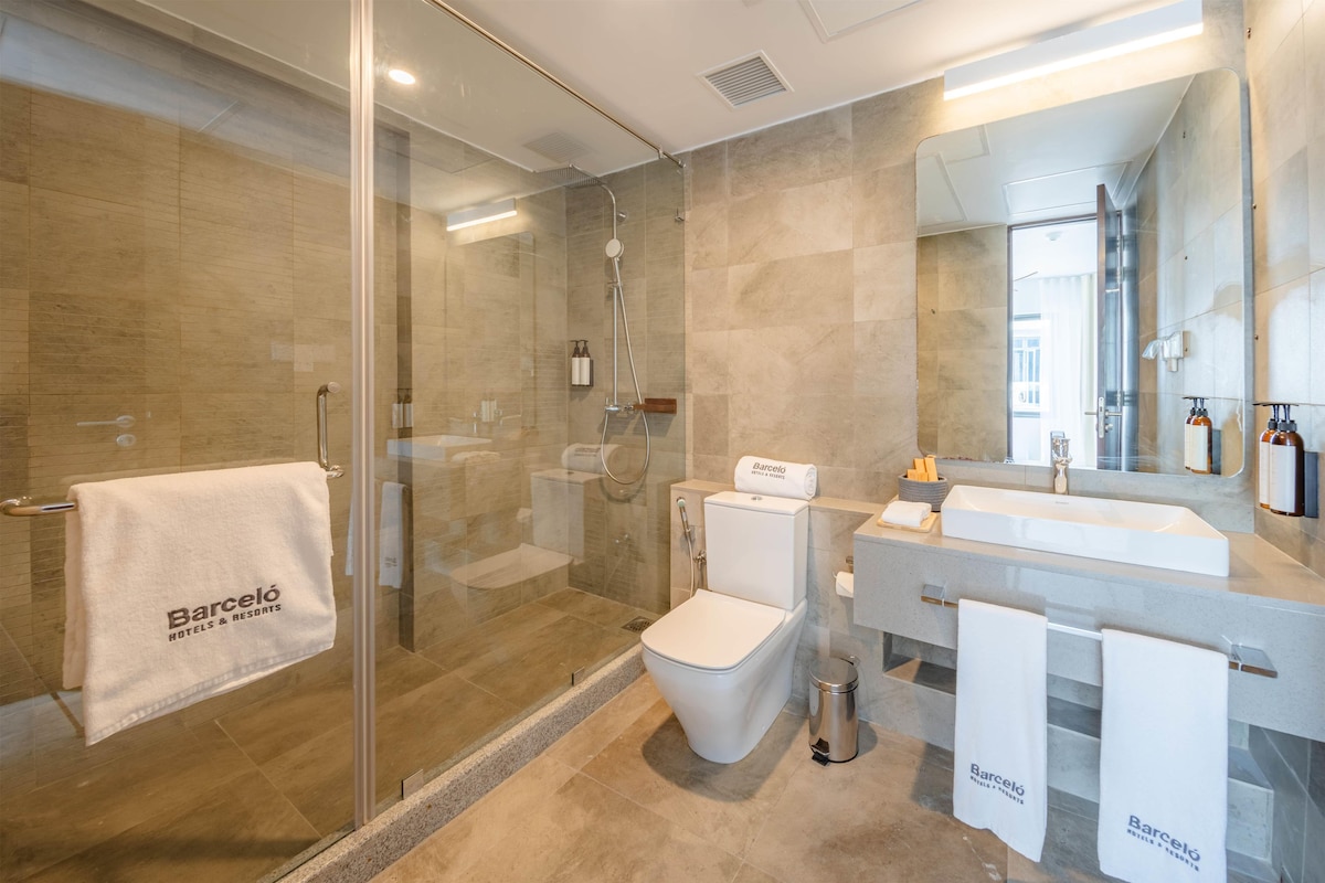A modern bathroom with a glass-enclosed shower, a white toilet, and a sink with a mirror above it.