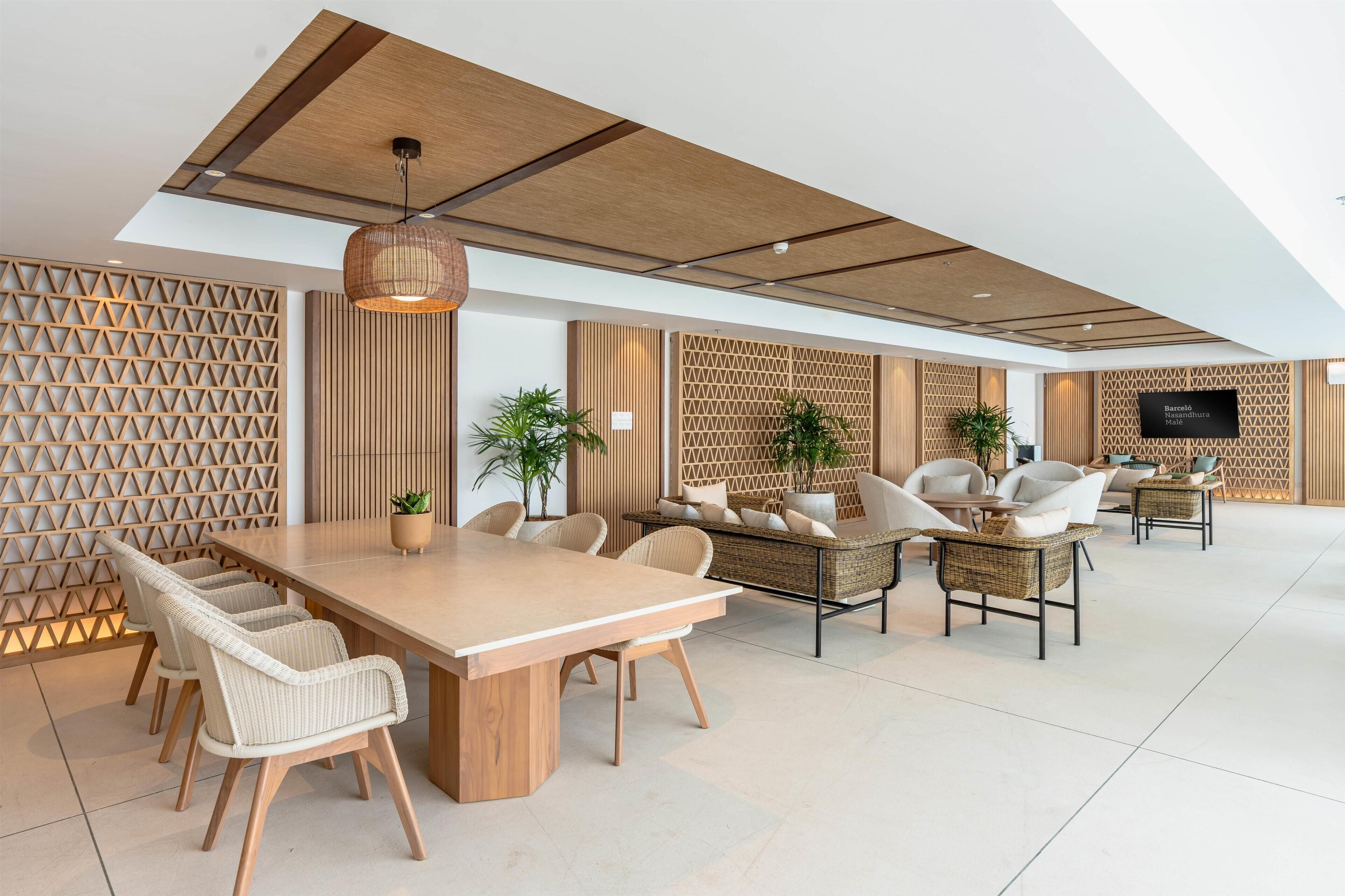A modern interior with a wooden dining table, wicker chairs, and a seating area with cushions.