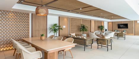 A modern interior with a wooden dining table, wicker chairs, and a seating area with cushions.