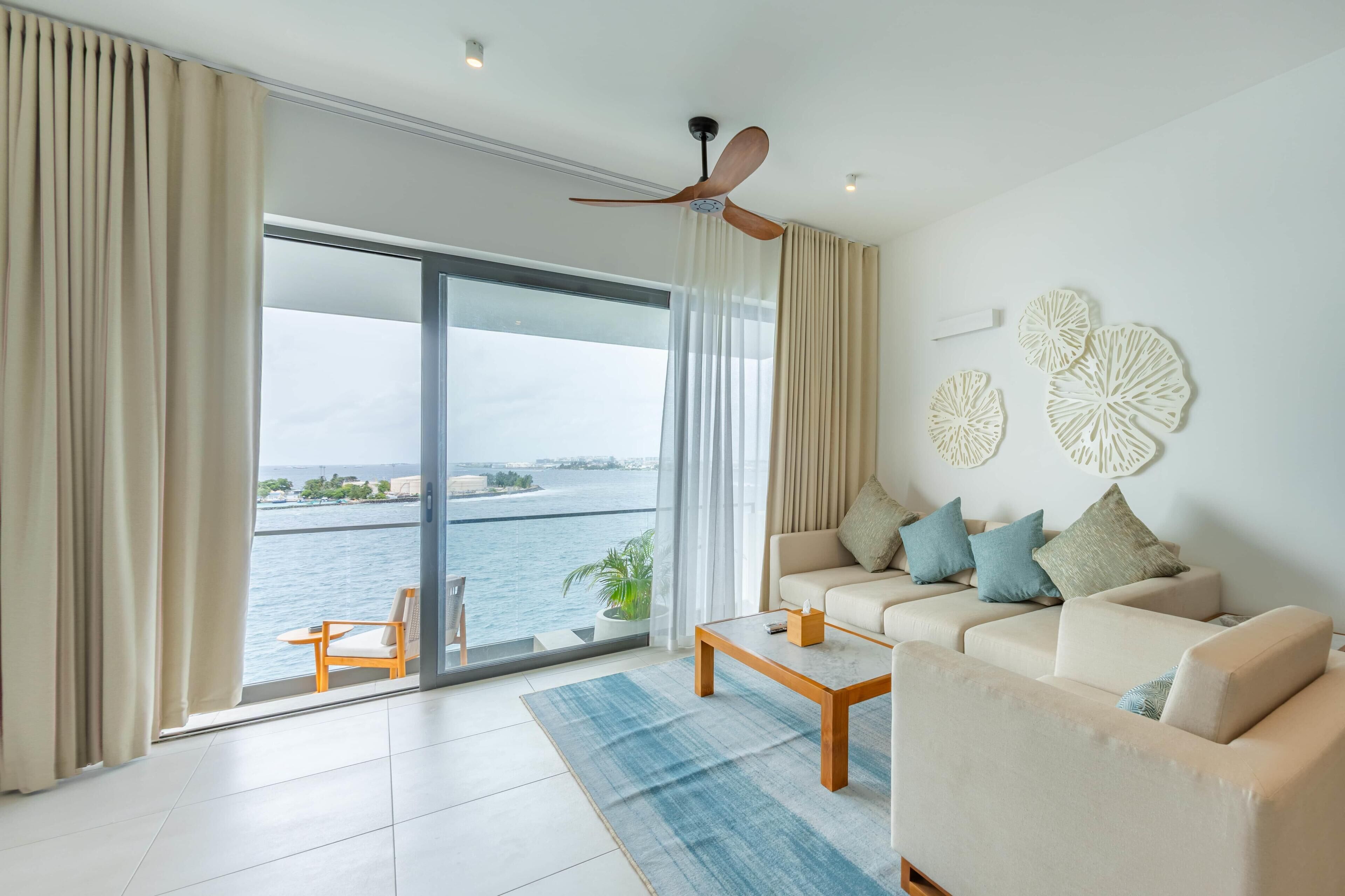 A modern living room with a sofa, coffee table, and a view of the water.
