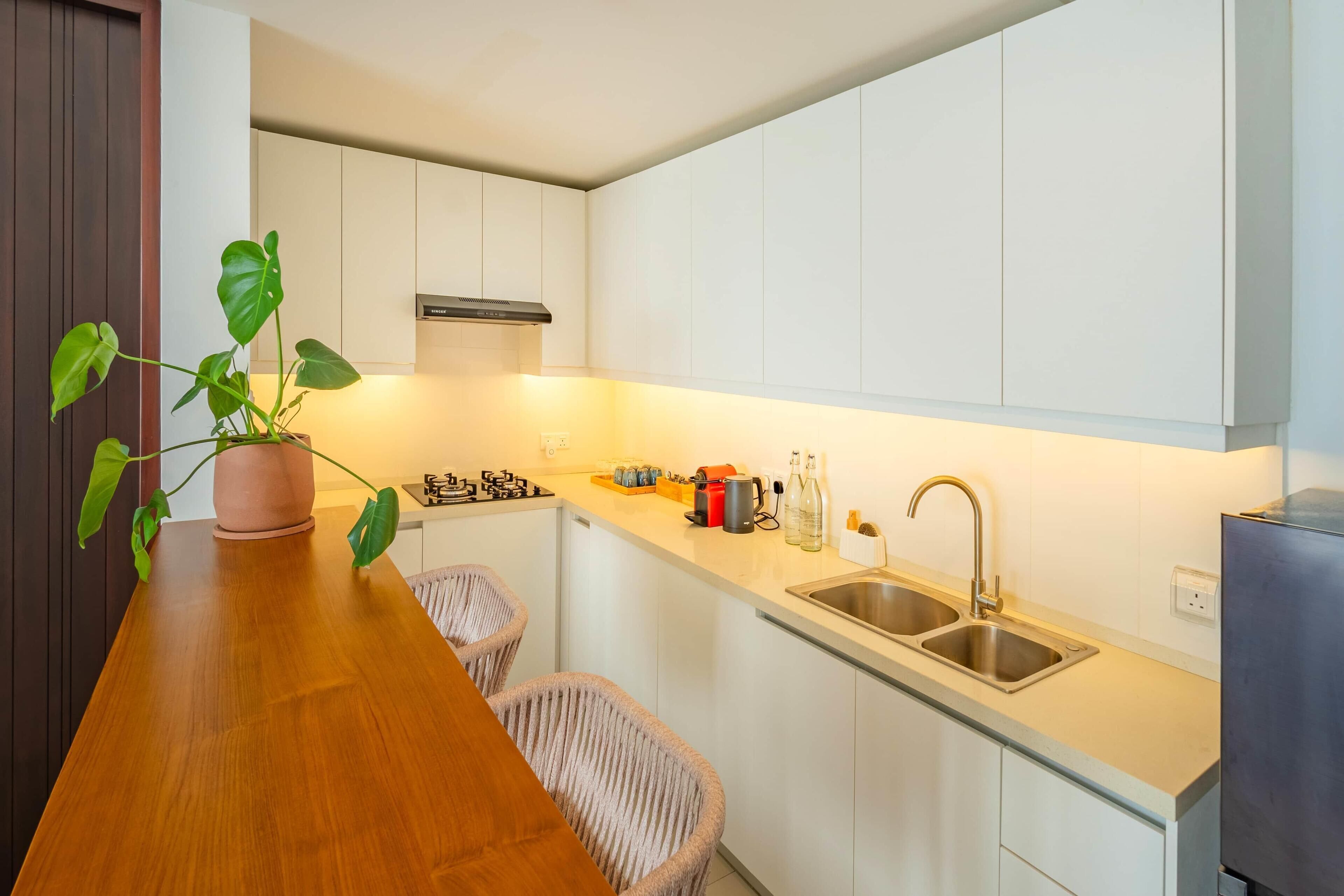 Una cocina moderna con armarios blancos, encimera de madera, estufa a gas, un lavabo y una planta en maceta.