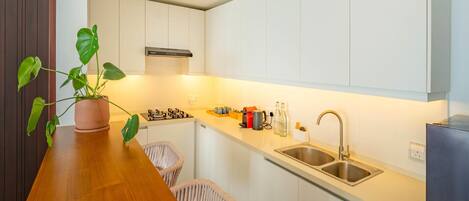 Una cocina moderna con armarios blancos, encimera de madera, estufa a gas, un lavabo y una planta en maceta.
