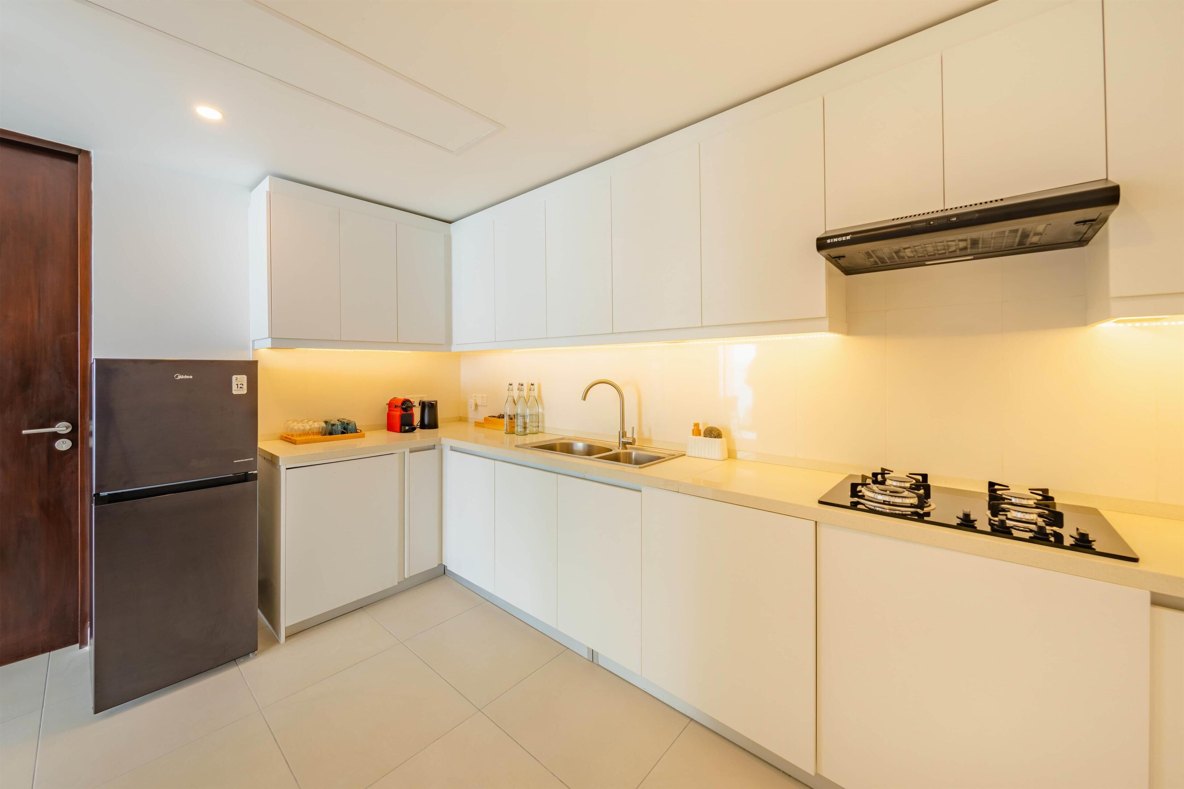 Een moderne keuken met witte kasten, een roestvrijstalen koelkast, een gasfornuis en een spoelbak.
