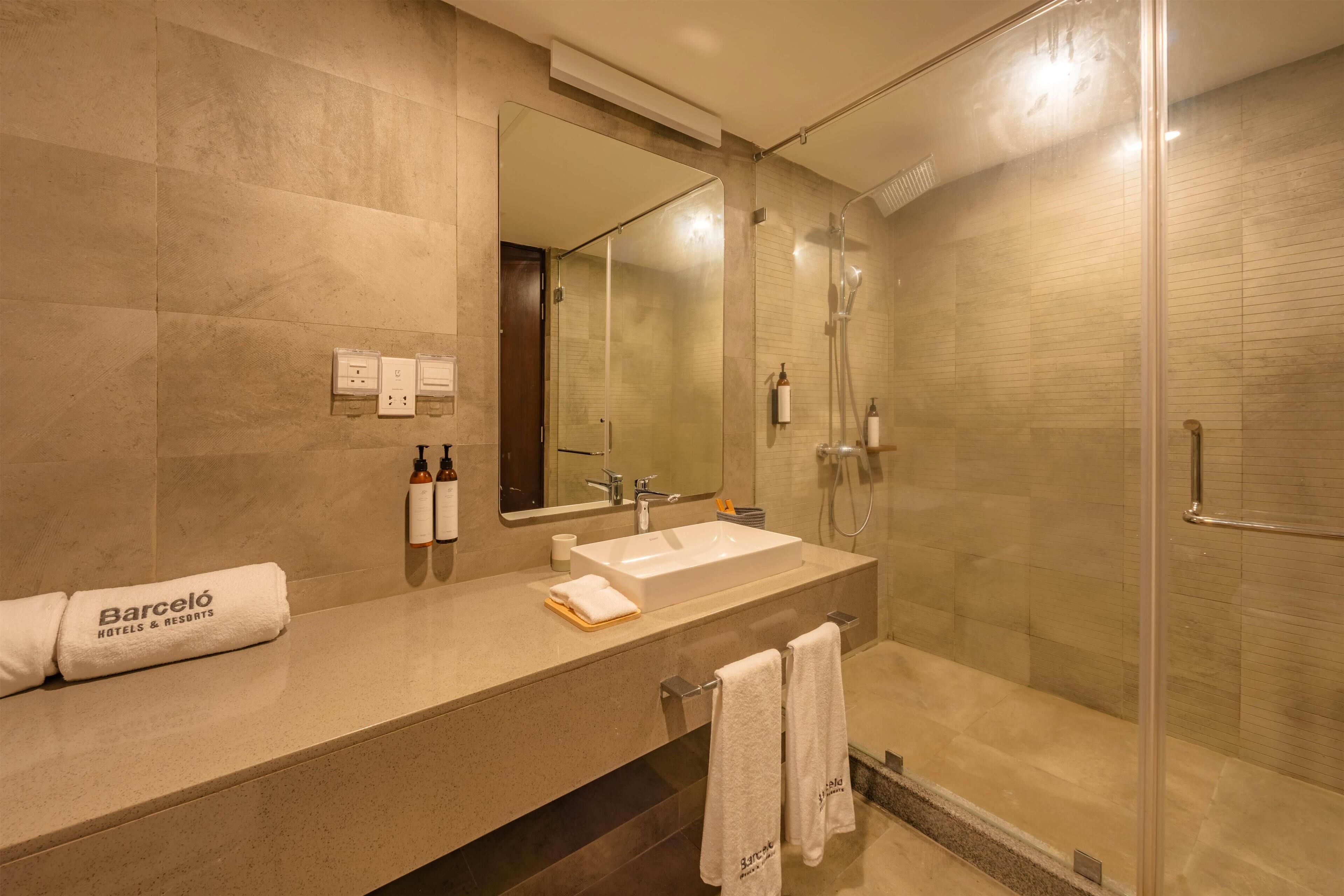 A modern bathroom with a glass-enclosed shower, a large mirror, and a vanity with a sink and towel rack.