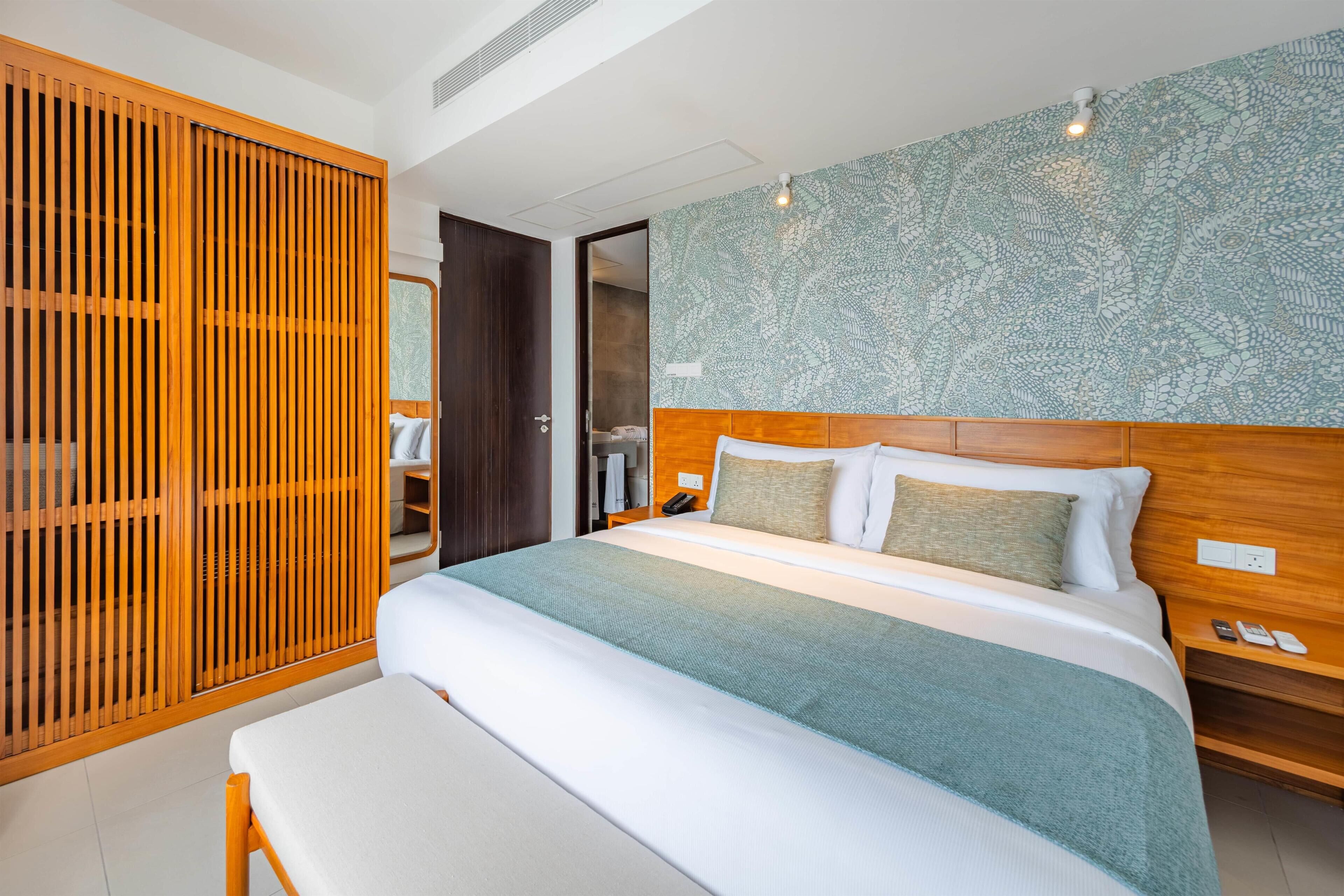 Una habitación de hotel moderna con una cama grande, cabecero de madera y un adorno en la pared.