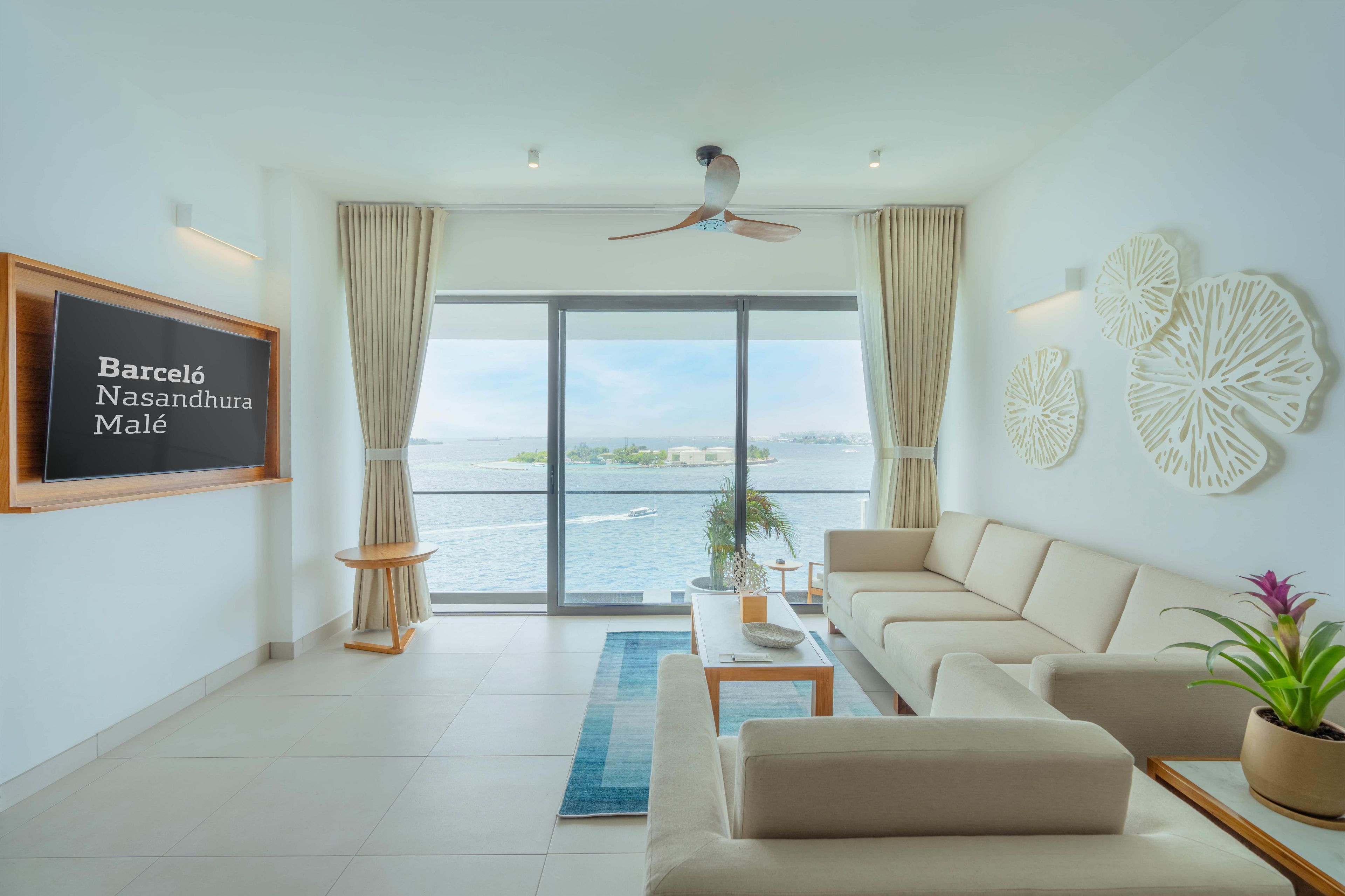 A modern living room with a large window, a ceiling fan, a flat-screen TV, and a sofa.