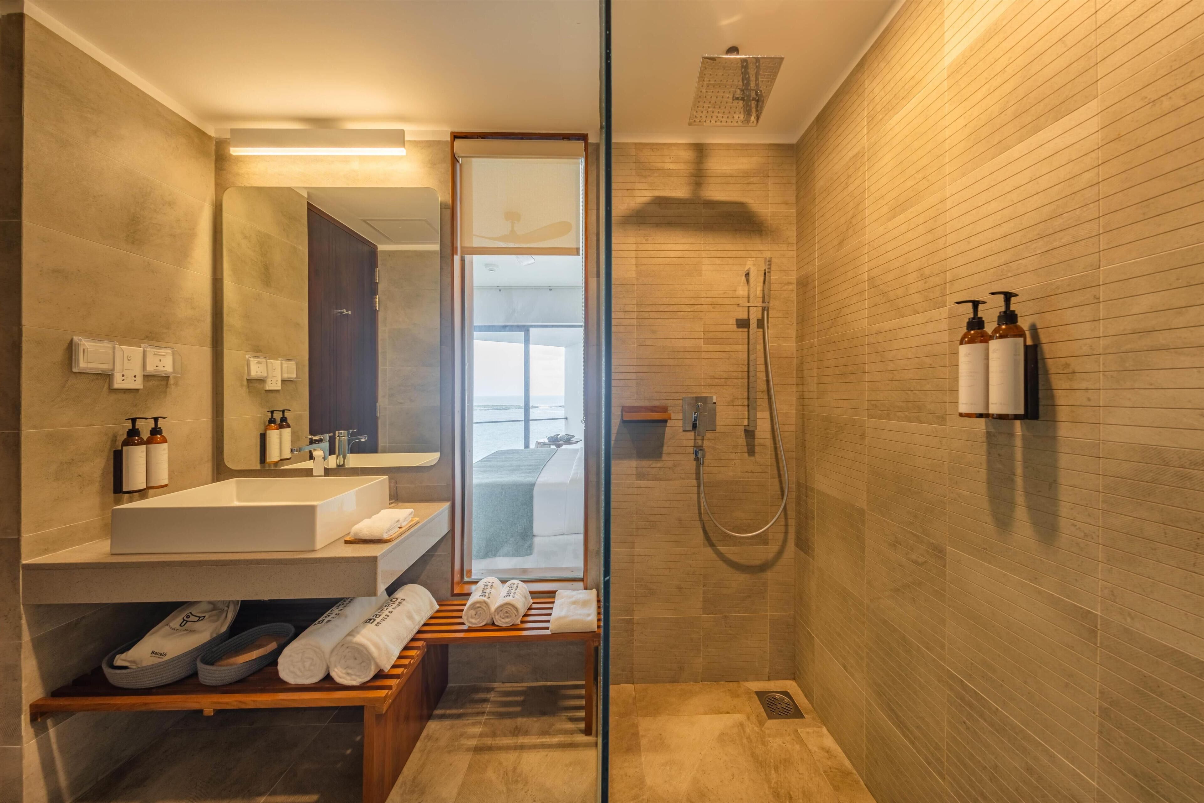 A modern bathroom with a glass shower enclosure, a sink with a mirror, and toiletries on the countertop.