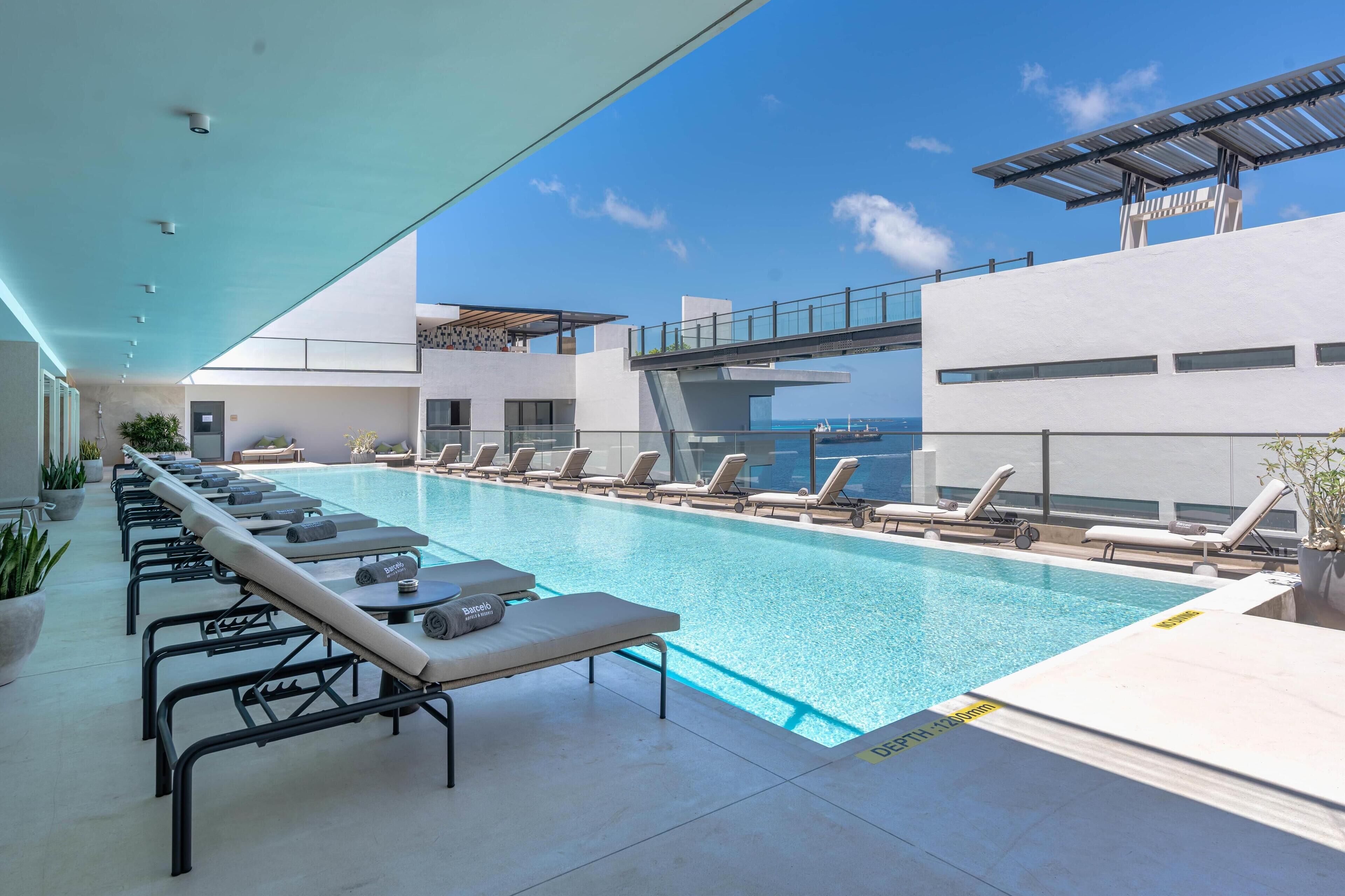 A modern pool area with lounge chairs and a glass bridge overlooking the pool.